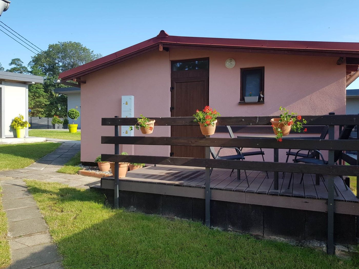 Domek letniskowy z tarasem, ławą i kwiatami w donicach